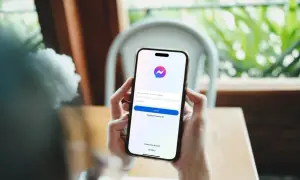 Dłonie trzymają smartfon z ekranem logowania Messengera. Dowiedz się, jak założyć czat na Messengerze, tworząc nowe konto.