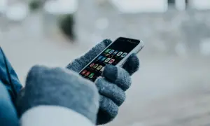 Ręka w rękawiczce trzyma smartfon z ikonami aplikacji. Chcesz wiedzieć, jak sprawdzić czy ktoś jest aktywny na Facebooku?