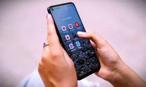 Dłonie trzymają telefon z ikonami aplikacji społecznościowych. Zastanawiasz się, jak trwale usunąć wiadomości z Messengera?