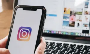 Telefon z logo Instagram. Na ekranie laptopa widać siatkę zdjęć, jakbyś chciał dowiedzieć się, jak wstawić czyjąś relację na swoją.