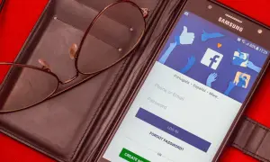 Okulary leżą na portfelu obok telefonu z ekranem logowania do Facebooka. Zastanawiasz się, czy usunięcie konta na FB i Messengera to dobry pomysł?