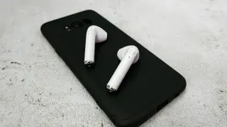 Białe słuchawki bezprzewodowe leżą na czarnym etui telefonu. Dowiedz się, jak sparować słuchawki Motorola.