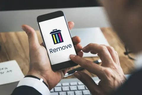 Dłoń trzyma smartfon z ikoną kosza i napisem "Remove". Dowiedz się, jak usunąć członka z grupy na Messengerze.