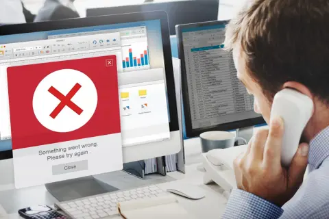 Błąd na ekranie komputera. Mężczyzna rozmawia przez telefon, próbując dowiedzieć się, jak usunąć się z administratora strony na FB.