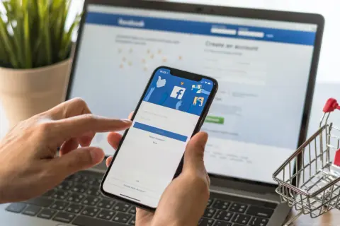 Ręce trzymające smartfon z ekranem logowania Facebooka. Dowiedz się, jak dodać email na FB, aby ułatwić sobie dostęp.