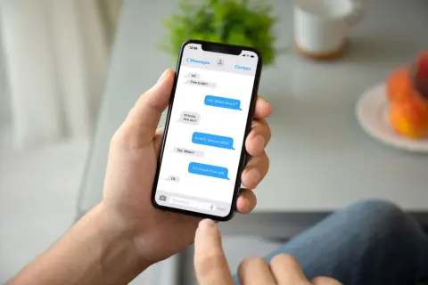 Dłoń trzyma smartfon z widocznym oknem czatu Messenger. Rozmowa dotyczy spotkania. Jak przywrócić wiadomości na Messengerze?
