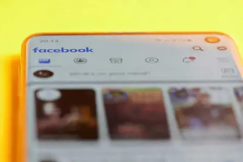 Telefon z aplikacją Facebook. Widoczna wyszukiwarka i ikony, które pomogą Ci znaleźć relacje na FB.