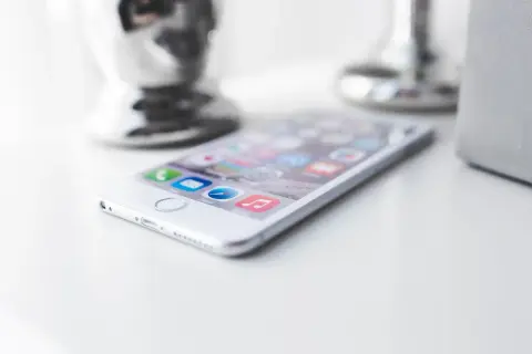 Biały iPhone na białym blacie. Zastanawiasz się, jak zmniejszyć pamięć Messengera? Oto wskazówka.