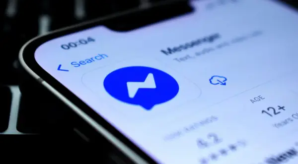 Szukasz sposobu, jak sprawdzić czy ktoś jest dostępny na Messengerze nie mając go w znajomych? Ekran telefonu z ikoną Messengera i opcją wyszukiwania.
