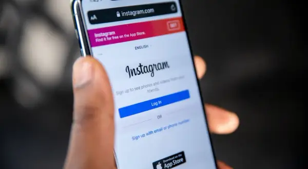 Dłoń trzyma smartfon z ekranem logowania Instagram. Dowiedz się, jak odzyskać skradzione konto na Instagramie, gdy widzisz ten ekran.