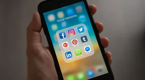Dłoń trzyma smartfon z ikonami sieci społecznościowych. Szukasz nicków dla chłopaka na Messengera? Tutaj znajdziesz inspiracje!