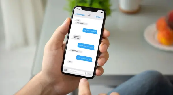 Dłoń trzyma smartfon z widocznym oknem czatu Messenger. Rozmowa dotyczy spotkania. Jak przywrócić wiadomości na Messengerze?