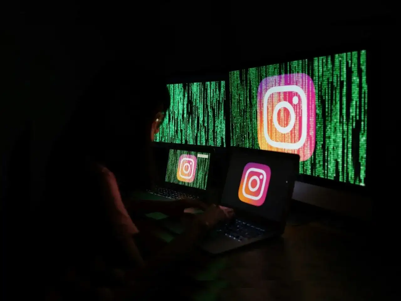 Osoba przy komputerze próbuje dowiedzieć się, jak odblokować konto na Instagramie. Na ekranach widnieje logo Instagrama na tle kodu.