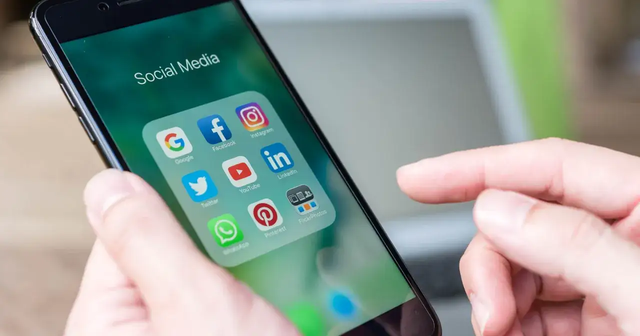 Palec wskazuje ikonę Facebooka na ekranie telefonu z folderem