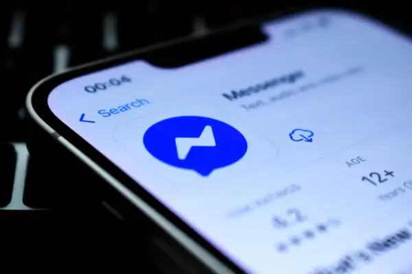 Szukasz sposobu, jak sprawdzić czy ktoś jest dostępny na Messengerze nie mając go w znajomych? Ekran telefonu z ikoną Messengera i opcją wyszukiwania.