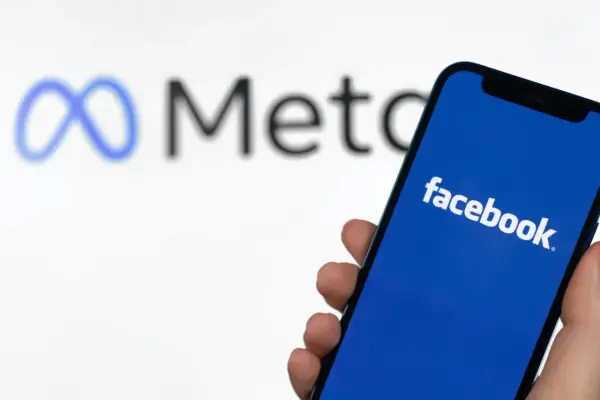 Chcesz wiedzieć, jak zmienić nr tel na FB? Na ekranie telefonu widać logo Facebooka, a w tle logo Meta.