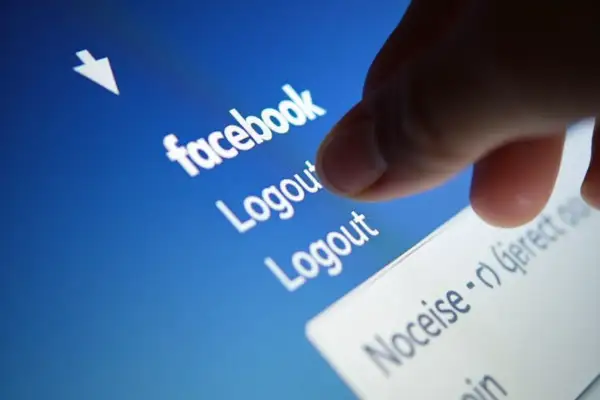 Palec dotyka opcji "Logout" na ekranie telefonu, pokazując, jak wylogować z Facebooka.