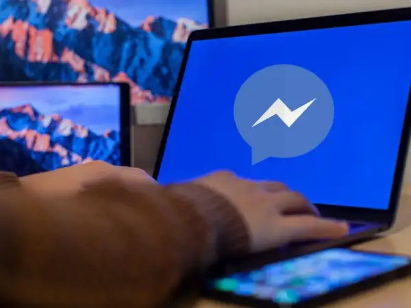 Dłoń na laptopie z logo Messengera. Dowiedz się, jak odzyskać cofniętą wiadomość Messenger.