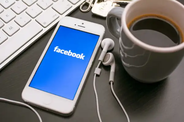 Telefon z Facebookiem, klawiatura i kawa. Dowiedz się, jak założyć konto szkoły na Facebooku, by być bliżej uczniów.