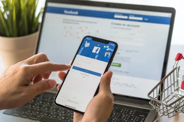 Ręce trzymające smartfon z ekranem logowania Facebooka. Dowiedz się, jak dodać email na FB, aby ułatwić sobie dostęp.