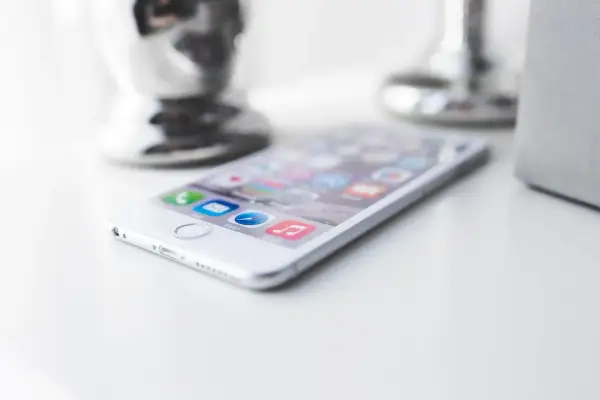 Biały iPhone na białym blacie. Zastanawiasz się, jak zmniejszyć pamięć Messengera? Oto wskazówka.
