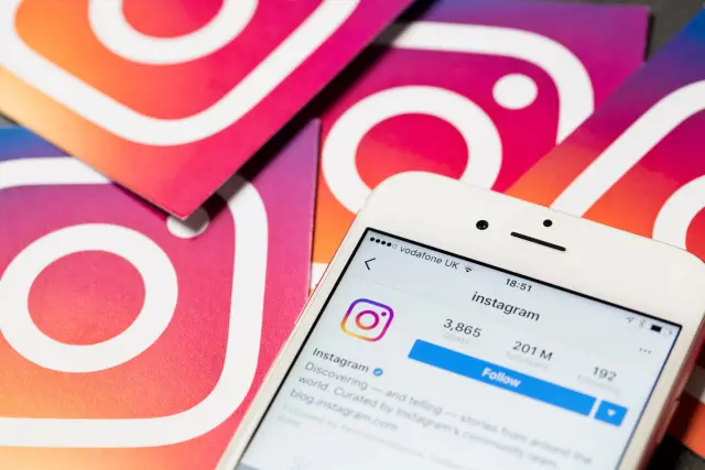 Telefon z profilem Instagram i logo aplikacji, symbolizujące zwiększenie zasięgu na Instagramie.